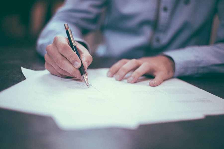 Mãos assinando um documento impresso sobre uma mesa de reunião